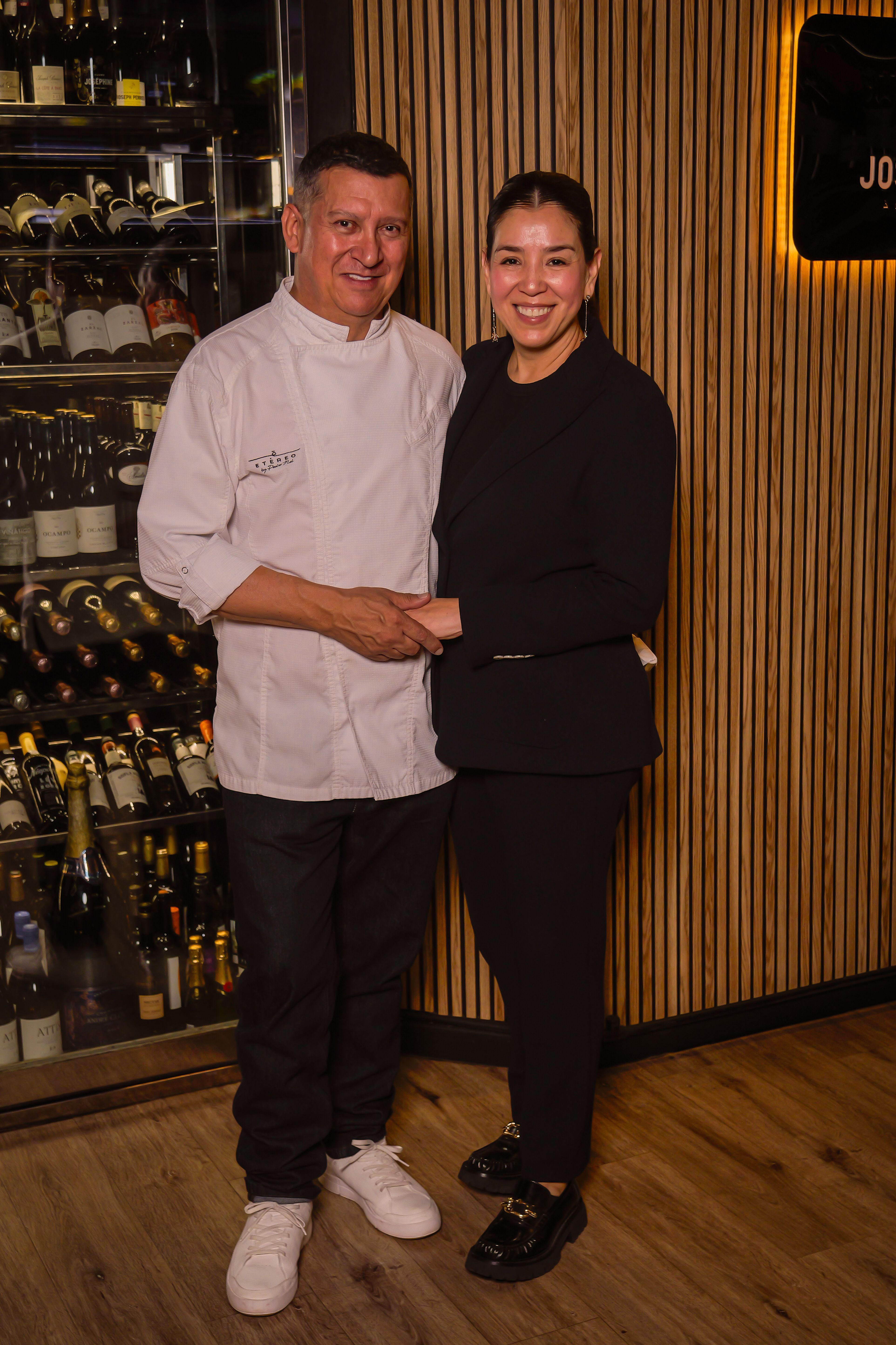 Pedro Nel, con la chaquetilla blanca de Etéreo, junto a una mujer vestida de negro delante de la bodega